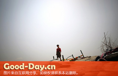 一名儿童站在贫民窟临时搭建房屋的选址旁
